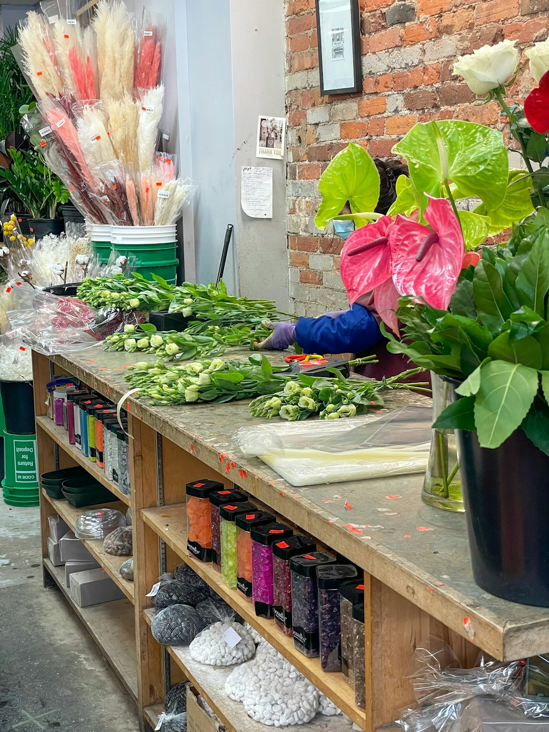 Florist som arrangerar ljusgröna blommor på en träbänk.