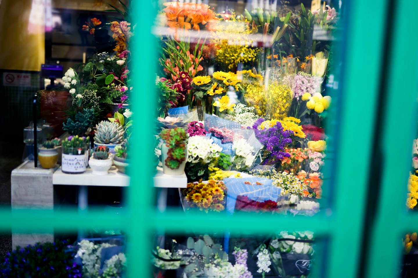 Färska blommor och kruksucculenter fyller ett blomsterbutiksfönster.