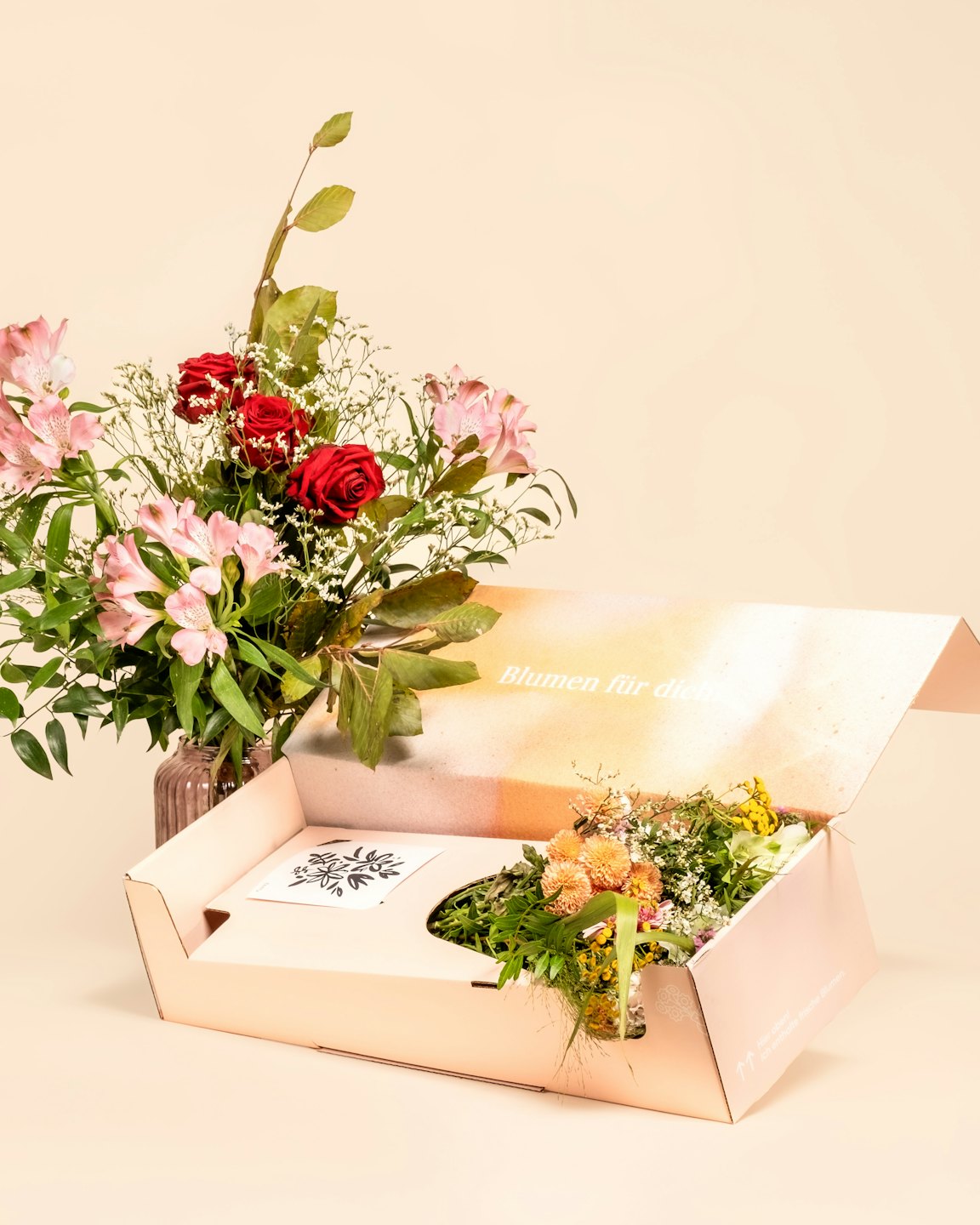 Blomsterleveranslåda med färska blommor bredvid en blomvas.