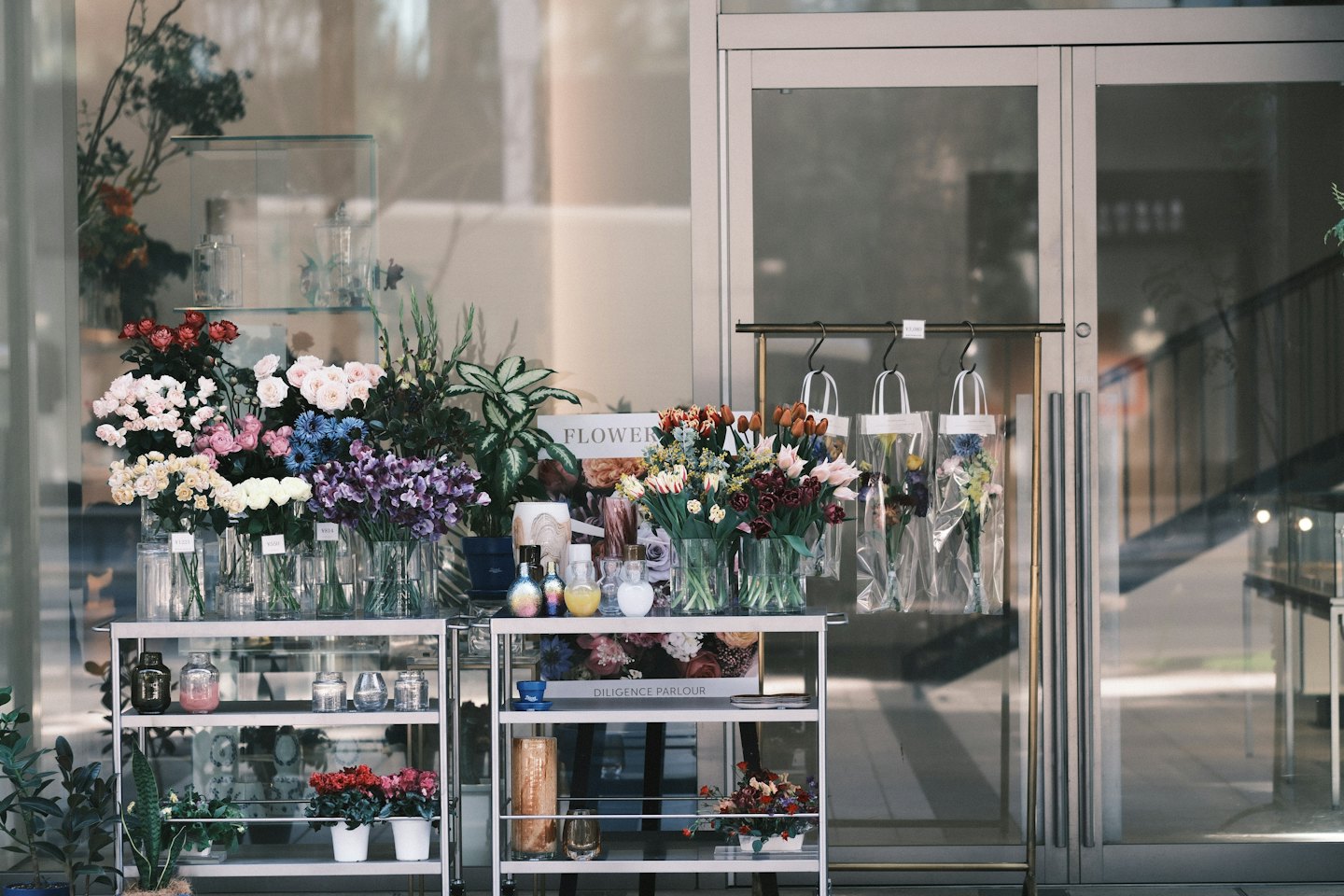 Blomsterbuketter och krukväxter uppställda utanför en modern blomsterbutik.