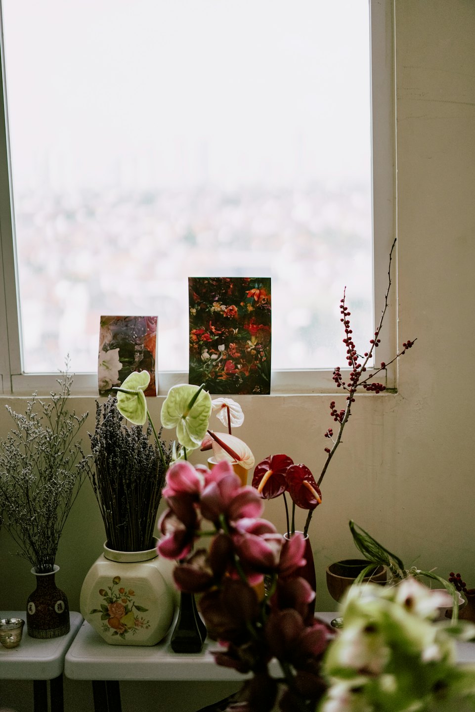 Färska och torkade blommor arrangerade i vaser på vita bord.