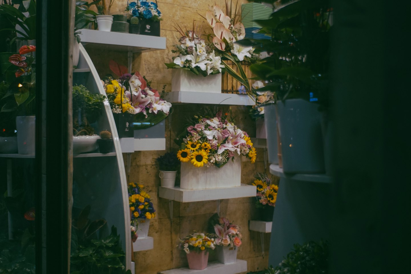 Blomsterarrangemang och krukväxter uppställda på butikshyllor.
